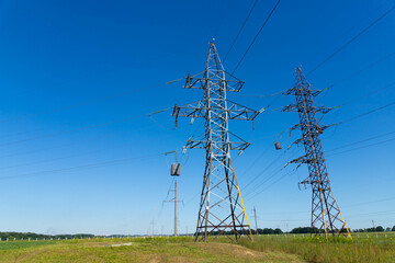 a high voltage power pylons against blue sky and sun rays