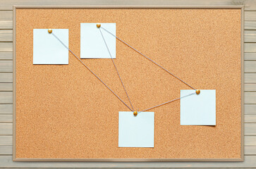 Blank paper notes are pinned to a cork board. The concept of detective investigation or training ....