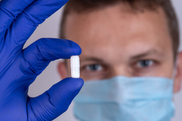 Man doctor woth tablet capsule in hands with gloves
