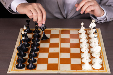 A man, a businessman plays chess, makes a move a black piece.
