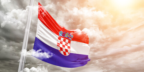 Croatia national flag cloth fabric waving on beautiful cloudy Background.