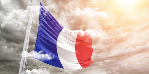 France national flag cloth fabric waving on beautiful cloudy Background.