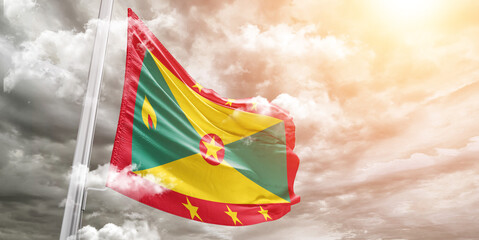 Grenada national flag cloth fabric waving on beautiful cloudy Background.