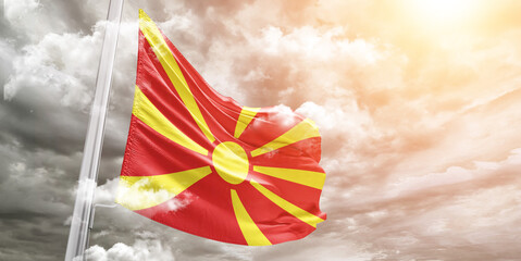 North Macedonia national flag cloth fabric waving on beautiful cloudy Background.