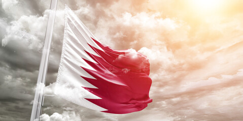 Qatar national flag cloth fabric waving on beautiful cloudy Background.