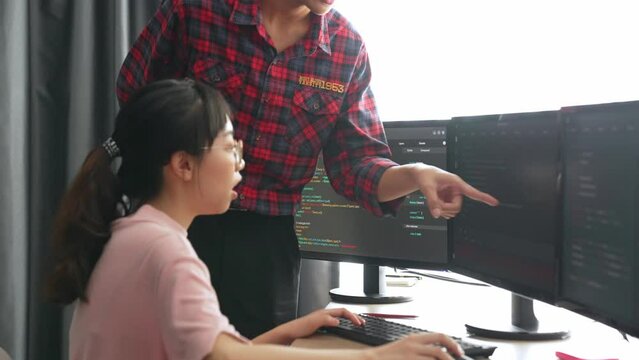 Back end or software developer manager supervising his team on new application program development on debugging and solving complex code algorithms on monitor. Burgeoning