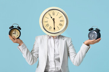 Young happy businesswoman with alarm clocks on blue background. Time management concept