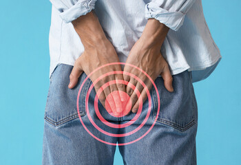 Young man with hemorrhoids on blue background, back view