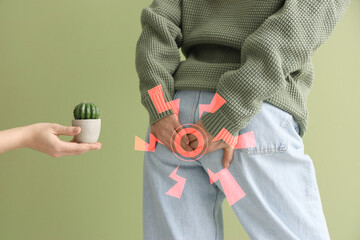 Mature woman and hand with cactus on green background, closeup. Hemorrhoids concept
