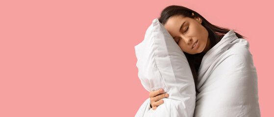 Sleepy young woman with blanket and pillow on pink background