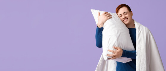 Handsome young happy man with blanket and pillow on purple background
