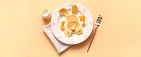 Funny Easter bunny pancakes with banana and mandarin on yellow background