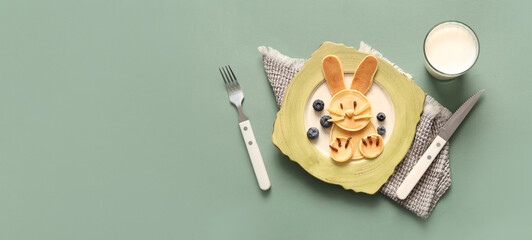 Funny Easter bunny pancakes with glass of milk on green background