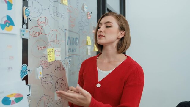 Closeup of young beautiful businesswoman with leadership presents the rocker sticker represent purpose, goal , skyrocket on glass board during creative business meeting start. Immaculate.