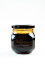 Jar of black honey on white background