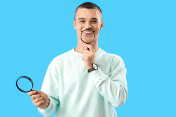 Young man with magnifiers  on blue background