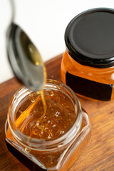 honey flows from a spoon into a jar