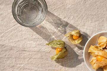 Healthy lifestyle nutrition concept, physalis berries and glass with water with aesthetic sunlight...