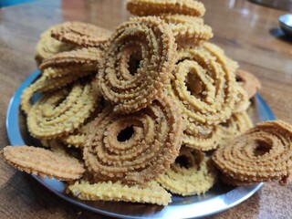 group of freshly fried spiral chakli snack placed in a plate