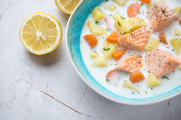 Lohikeitto or finnish soup with salmon, horizontal shot on a white granite surface, middle closeup, selective focus