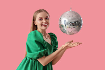 Beautiful stylish woman with disco ball on pink background