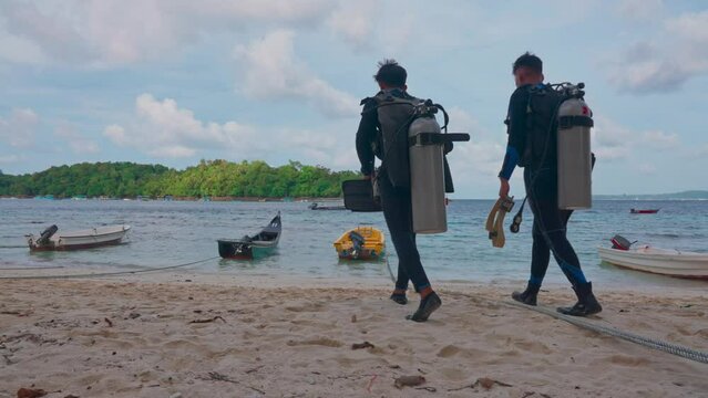 Divers walk towards the boat in diving suit and scuba gear