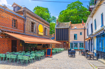 Street restaurants with tables and chairs near old brick buildings in Amiens historical city centre, cozy cafe in old town Saint-Leu quarter, Somme department, Hauts-de-France Region, Northern France