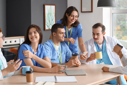 Team of young doctors having lunch at table in hospital kitchen