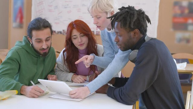 Diverse multiethnic students or friends gathered around a tablet in a university classroom - engaging in collaborative study, academic innovation - Multicultural Study Group