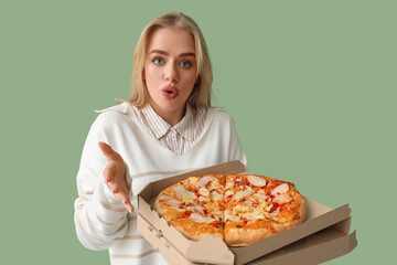 Surprised beautiful woman with tasty pizza on green background