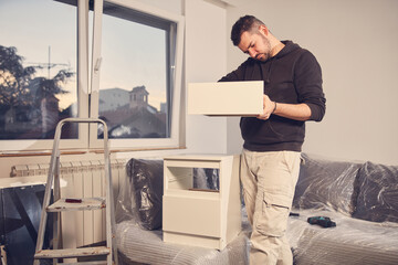 Man working and assembling furniture in a new apartment.
