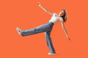 Young woman in stylish jeans on orange background - obrazy, fototapety, plakaty