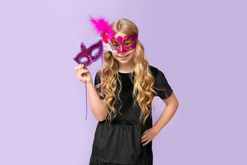 Funny little girl with carnival masks on lilac background