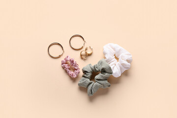 Silk scrunchies with earrings on beige background