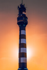 Naklejka premium Lighthouse against the backdrop of sunset. Scarlet crimson sunset