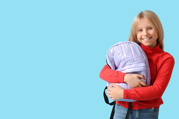 Cute schoolgirl with backpack on blue background