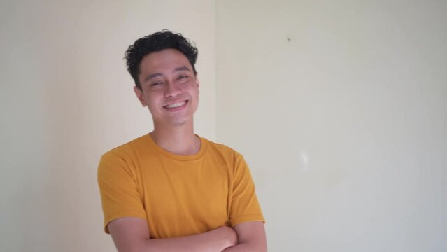 Young Indonesian curly man wear yellow t-shirt cheers and victory pose. The footage is suitable to use for man expression and people advertising content media.