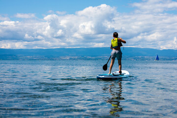 Enfant apprenant le stand up paddle sur les eaux calmes du lac Léman, Evian-les-Bains, Haute-Savoie