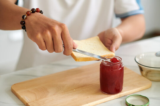 Closeup image of man spreading jam on piece of bread