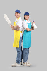 Workers of cleaning service with supplies on light background