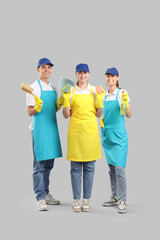 Workers of cleaning service with supplies on light background