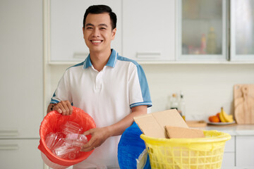 Portrait of smiling Vietnamese man sorting waste at home