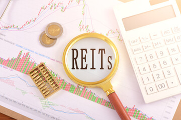 The magnifying glass on the chart is printed with the letter REITS - obrazy, fototapety, plakaty