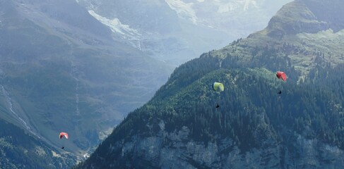 Paragliders soar over a majestic mountain range