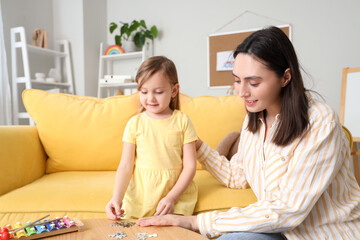 Naklejka premium Female psychologist with little girl doing puzzle in office