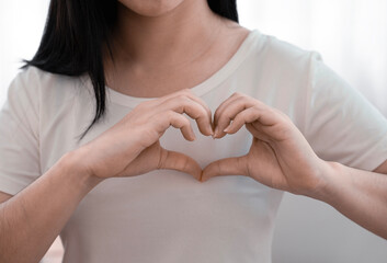 woman making hand-shaped heart, heart health insurance concept. world mental health, cancer day,  world heart day, organ donor.
