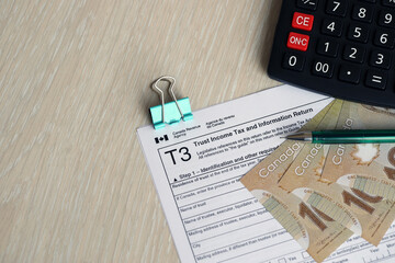 Canadian T3 tax form Trust income tax and information return lies on table with canadian money...