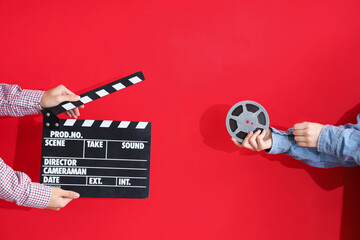 Hands with movie clapper and film reel on red background