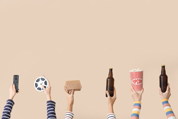Many hands with bucket of popcorn, TV remote and beer on beige background