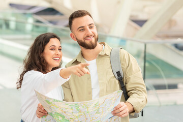 Couple with map smiling and pointing somewhere